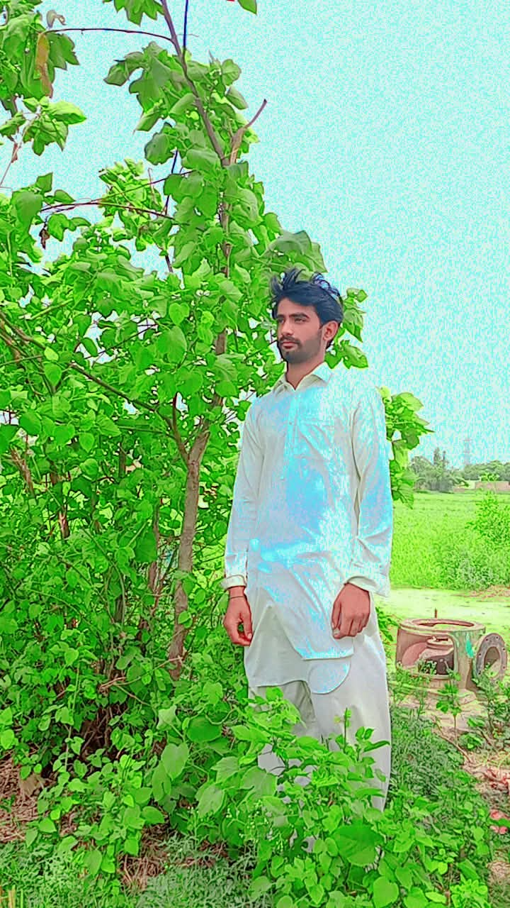 Nika Don standing beside a leafy tree in a green landscape